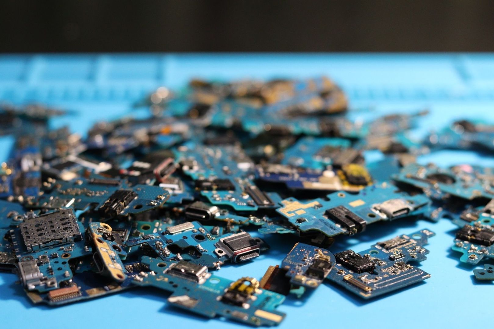 Disassembled smartphone circuit boards and electronic components on a blue surface