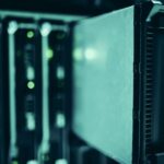 Close-up of dark server racks with glowing green indicator lights