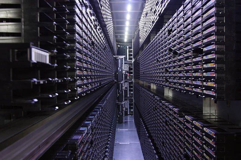 Rows of archival data storage cartridges lining a dark server aisle